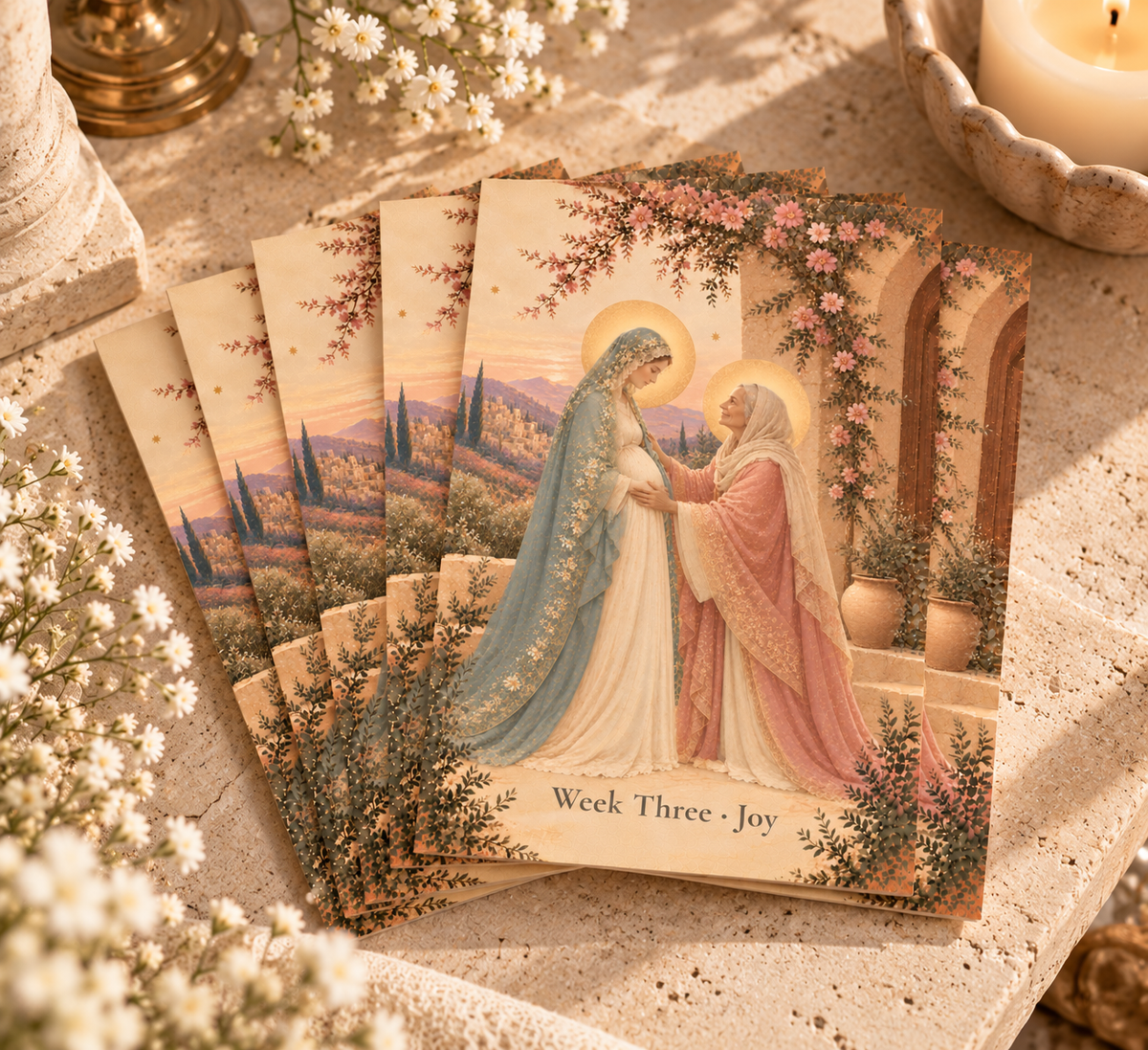 Set of Week Three Joy Advent prayer cards of the Visitation fanned out on travertine stone